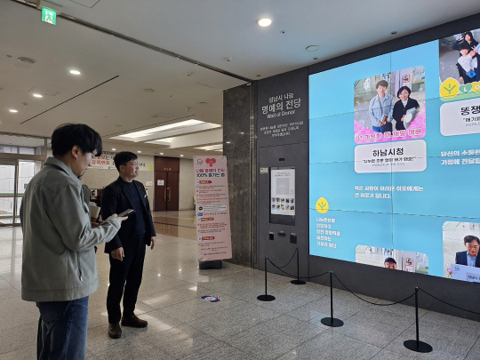 성남시청 로비에 설치된 '나눔 명예의 전당'을 벤치마킹 하는 하남시 방문단/사진제공=성남시